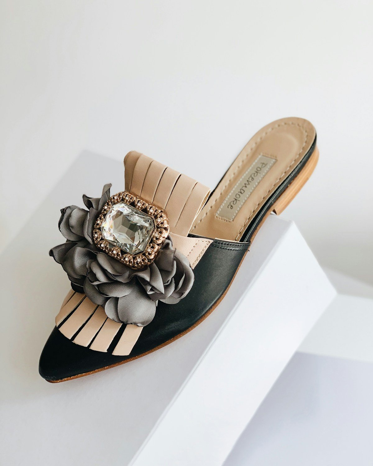 Black and beige pointed-toe mule with a fabric flower and large decorative stone